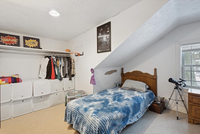 bedroom with light carpet, vaulted ceiling, and a textured ceiling