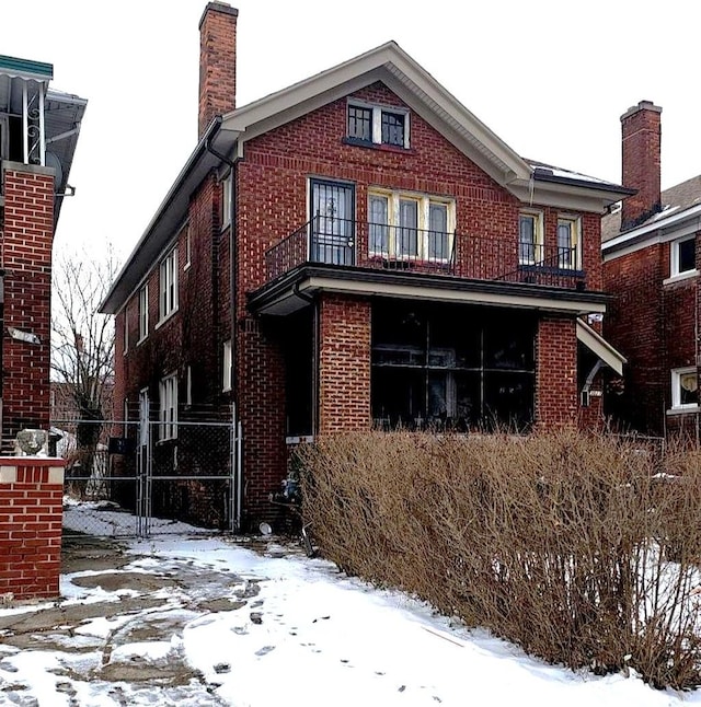 snow covered back of property with a balcony