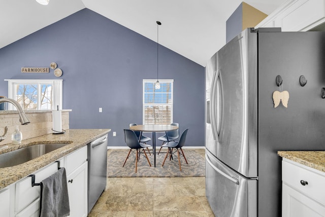 kitchen with appliances with stainless steel finishes, sink, white cabinetry, decorative light fixtures, and light stone countertops