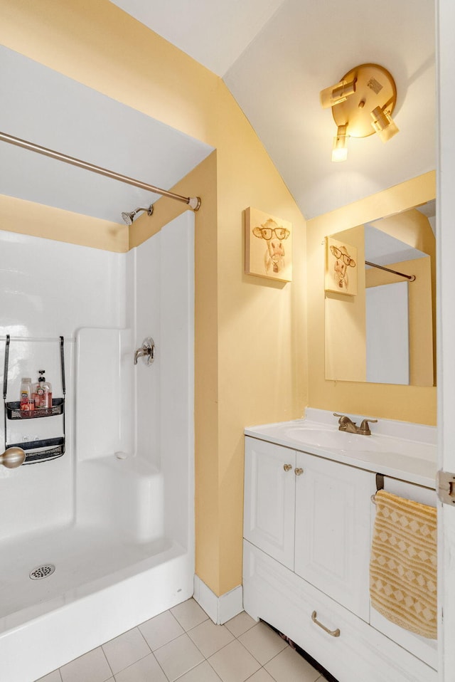 bathroom featuring tile patterned floors, vanity, walk in shower, and vaulted ceiling