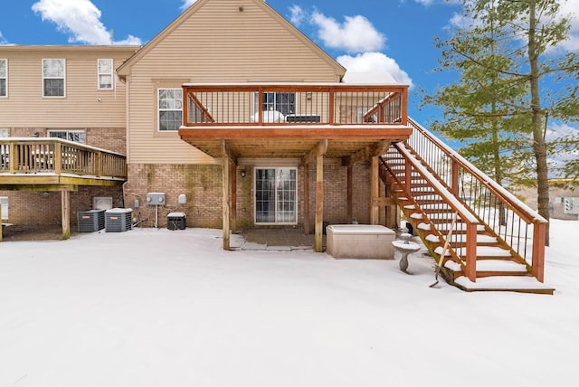 snow covered back of property featuring a wooden deck and central AC unit