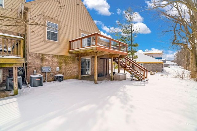 snow covered back of property featuring a wooden deck and central AC