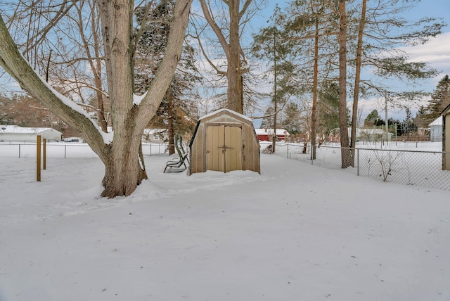 yard covered in snow with a shed and fence