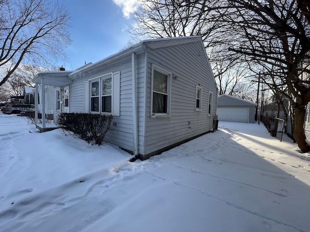 snow covered property featuring a garage and an outdoor structure