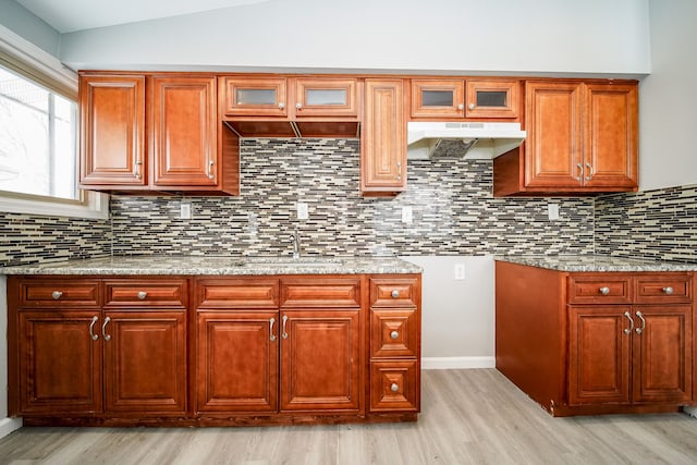 kitchen featuring sink, light stone counters, light hardwood / wood-style floors, and lofted ceiling