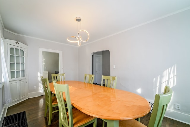 dining space featuring arched walkways, crown molding, dark wood finished floors, a chandelier, and baseboards