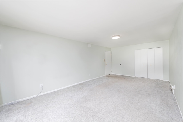 unfurnished bedroom featuring light carpet, baseboards, and a closet