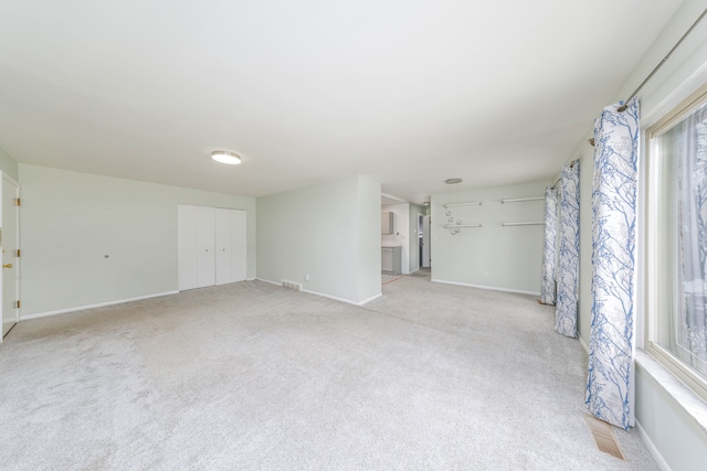 spare room featuring light carpet and baseboards