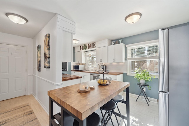 kitchen with appliances with stainless steel finishes, decorative backsplash, sink, and white cabinets