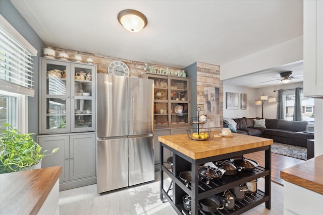 kitchen featuring ceiling fan, wood counters, gray cabinetry, and stainless steel fridge