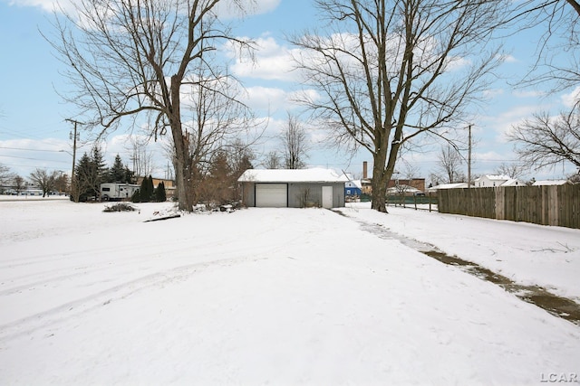 snowy yard featuring a garage and an outdoor structure