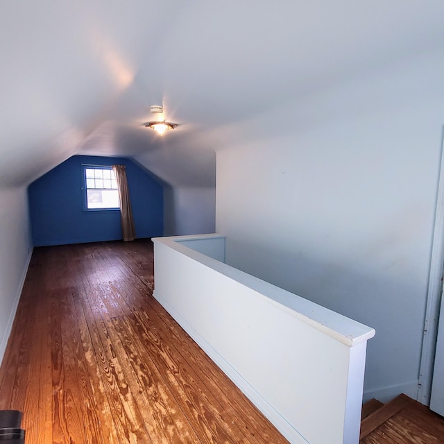 additional living space featuring dark wood-type flooring and lofted ceiling