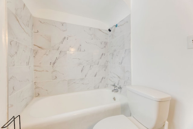 bathroom with tiled shower / bath combo and toilet