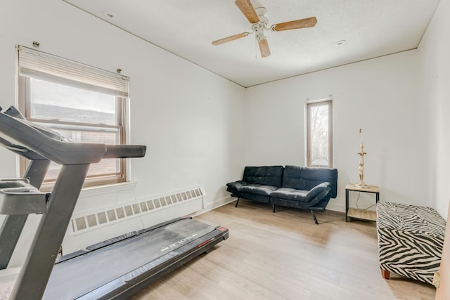 exercise area with light hardwood / wood-style flooring, ceiling fan, radiator, and a textured ceiling