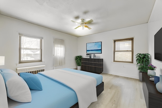 bedroom featuring light hardwood / wood-style floors, ceiling fan, and radiator