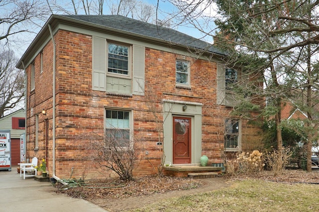 view of front of house with a chimney and brick siding