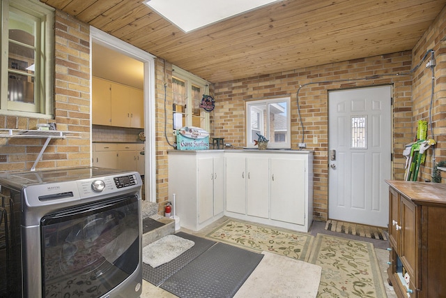 kitchen featuring brick wall, washer / clothes dryer, white cabinets, and wooden ceiling