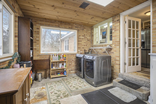 laundry room with brick wall, wood ceiling, and washing machine and clothes dryer