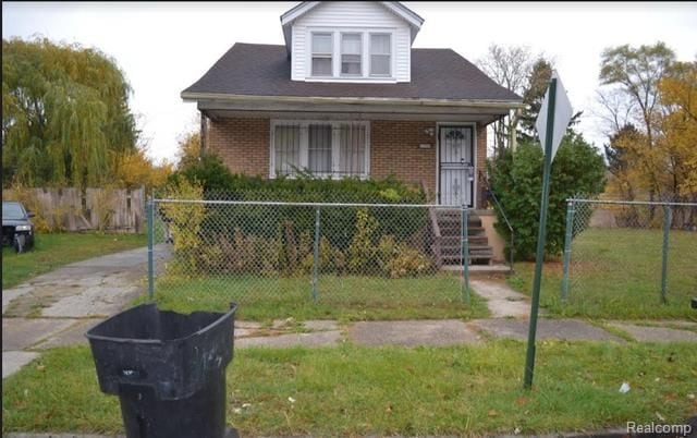 bungalow featuring a fenced front yard, brick siding, and a front yard