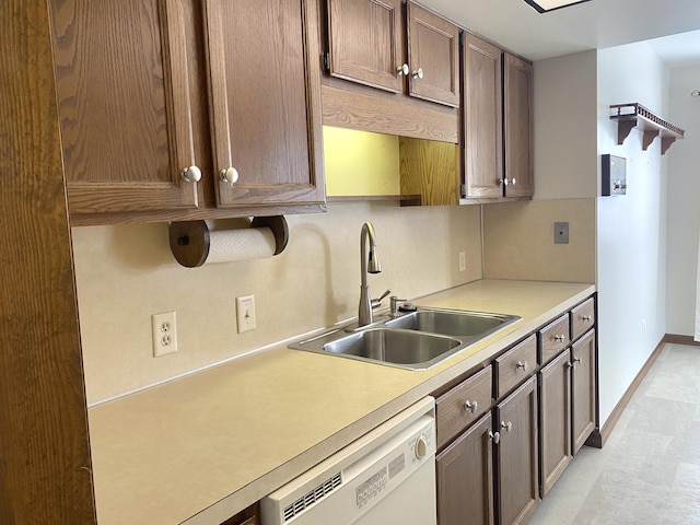 kitchen featuring white dishwasher, baseboards, a sink, and light countertops