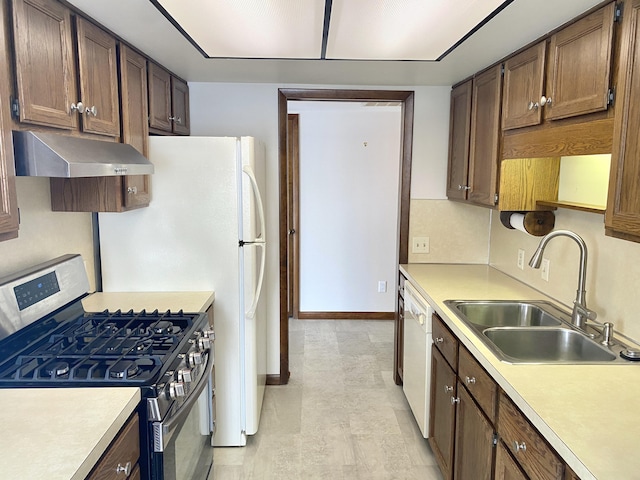 kitchen featuring gas stove, range hood, a sink, and light countertops