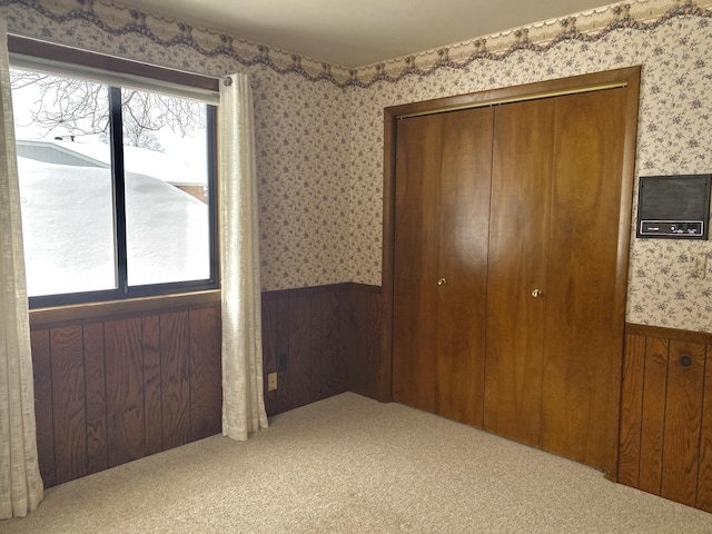 unfurnished bedroom featuring wallpapered walls, a wainscoted wall, and multiple windows