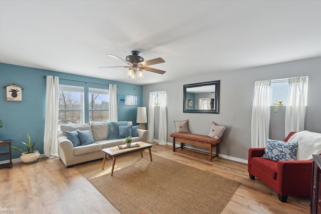 living room featuring light wood-style flooring, baseboards, and a ceiling fan