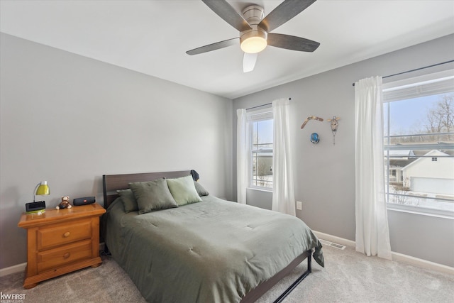 bedroom featuring baseboards, light colored carpet, visible vents, and ceiling fan