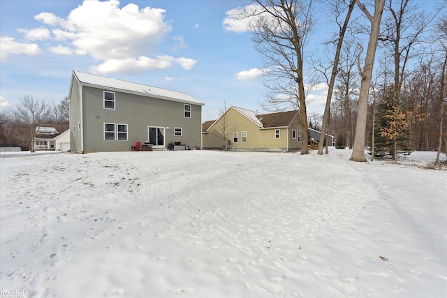 snow covered rear of property featuring a garage