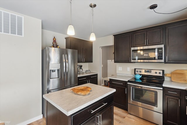 kitchen featuring dark brown cabinets, visible vents, a center island, appliances with stainless steel finishes, and light countertops