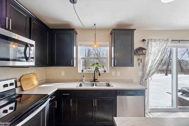 kitchen with light countertops, pendant lighting, appliances with stainless steel finishes, a healthy amount of sunlight, and a sink