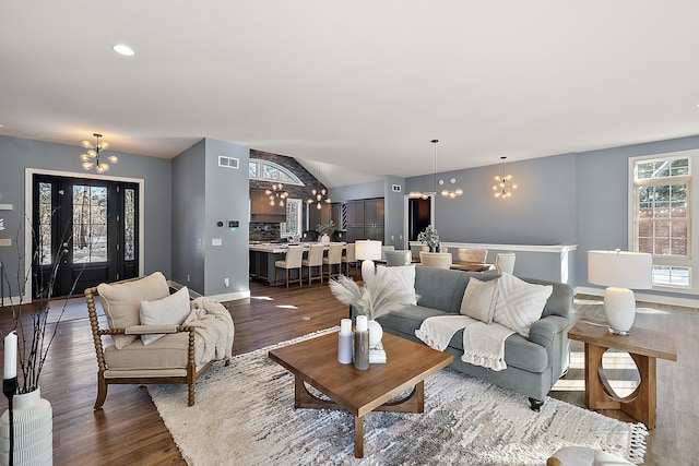 living area featuring dark wood finished floors, a chandelier, and vaulted ceiling