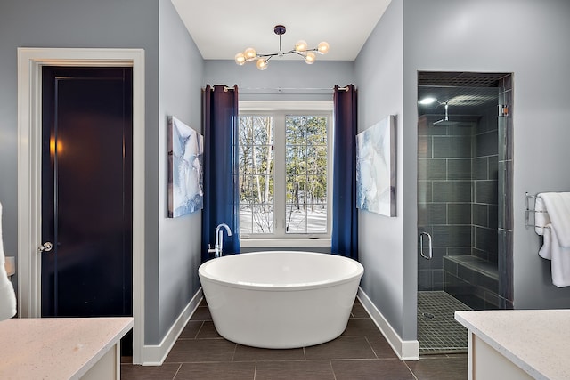 bathroom with vanity, a freestanding bath, a shower stall, baseboards, and a notable chandelier