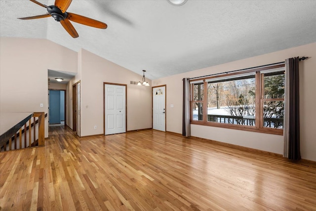 spare room featuring baseboards, vaulted ceiling, a textured ceiling, and light wood finished floors