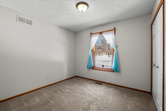 spare room with carpet floors, visible vents, and baseboards