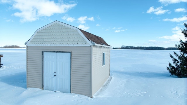 snow covered structure with an outbuilding and a shed