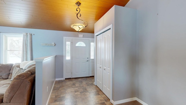 entryway with vaulted ceiling, baseboards, wood ceiling, and stone finish floor