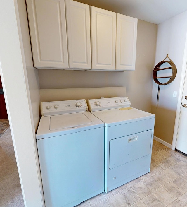 clothes washing area featuring baseboards, washing machine and clothes dryer, and cabinet space