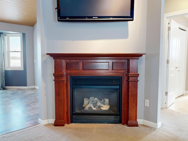 details featuring a glass covered fireplace, carpet floors, and baseboards