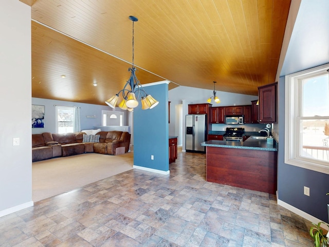 kitchen with appliances with stainless steel finishes, baseboards, dark countertops, open floor plan, and a sink