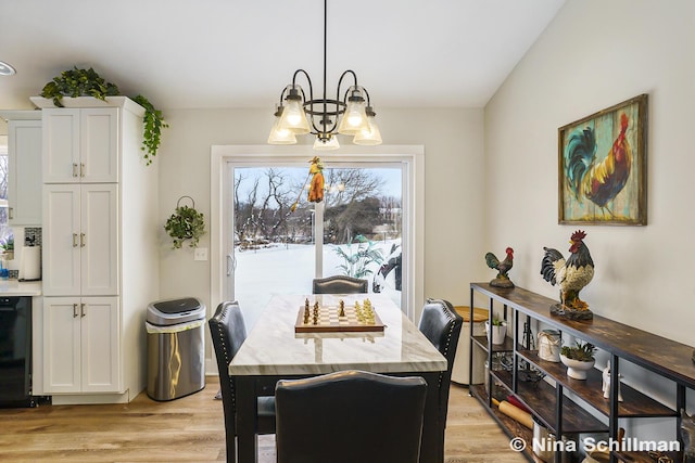 dining space with a notable chandelier, vaulted ceiling, and light wood finished floors