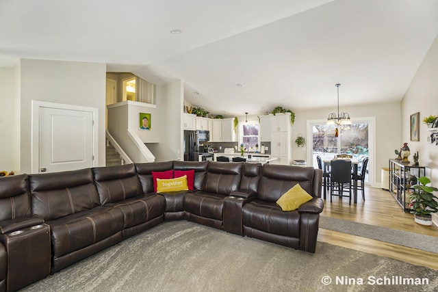 living room with light wood-type flooring, stairway, vaulted ceiling, and an inviting chandelier