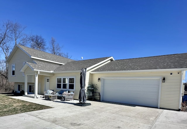 view of front of house featuring a shingled roof, concrete driveway, outdoor lounge area, a garage, and a patio