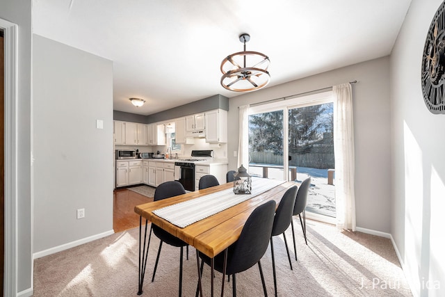 dining area featuring a chandelier, light carpet, and baseboards