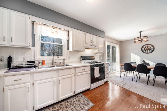 kitchen featuring a sink, gas range, white cabinets, and light countertops