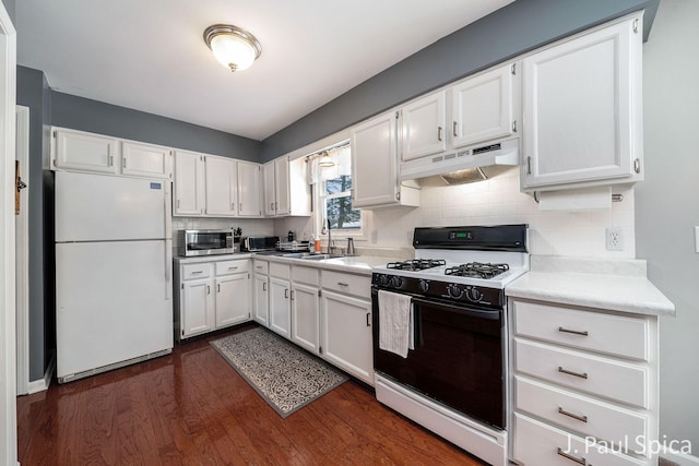 kitchen featuring gas range, white cabinets, freestanding refrigerator, and under cabinet range hood