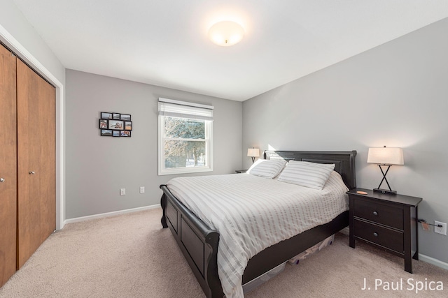 bedroom featuring baseboards, light colored carpet, and a closet