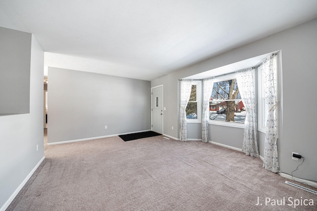 foyer entrance featuring baseboards and light colored carpet