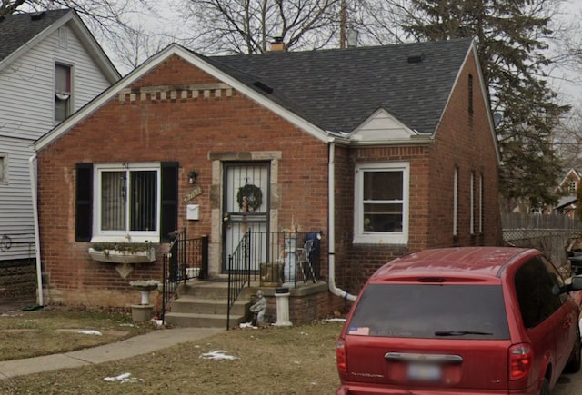 view of front of house with brick siding, a chimney, and roof with shingles