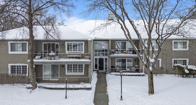 snow covered back of property with brick siding